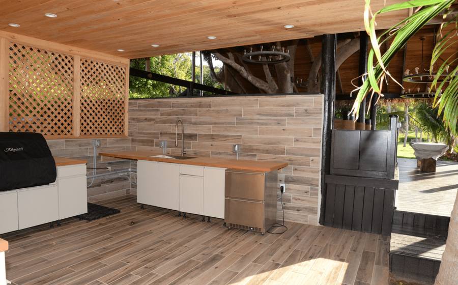 Built-in outdoor kitchen with grill and counters under a covered patio