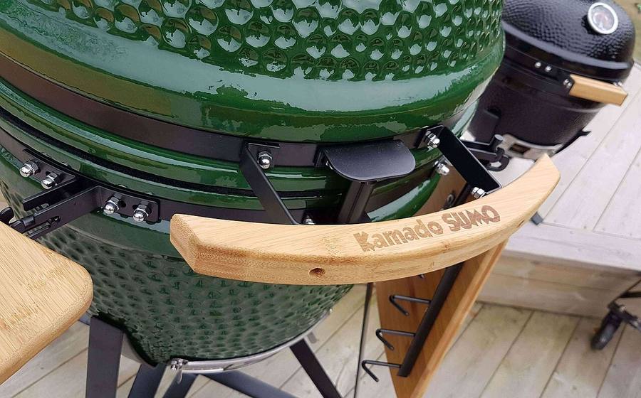 Green ceramic kamado grill with side shelf on a wooden deck