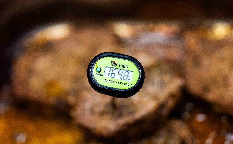 Digital probe thermometer reading internal temperature in grilled meat (representative photo)