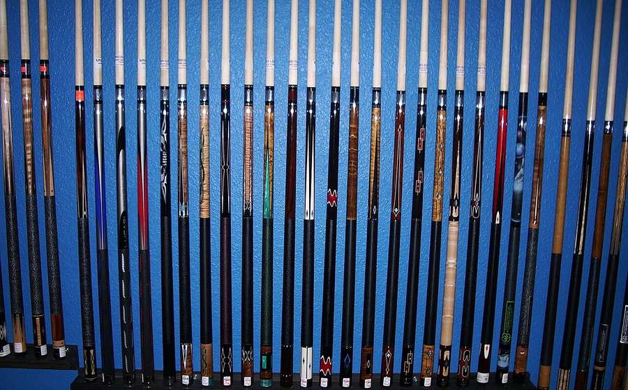 Row of precision pool cues on a wall rack