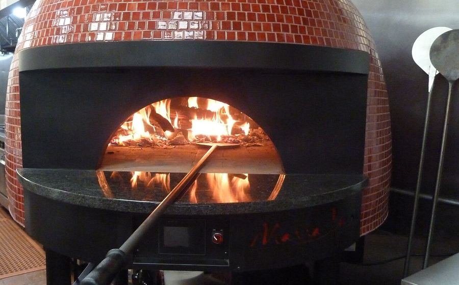 Tiled dome pizza oven with a live flame inside