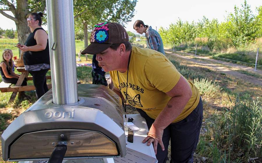 Cook checking a pizza in a portable outdoor pizza oven